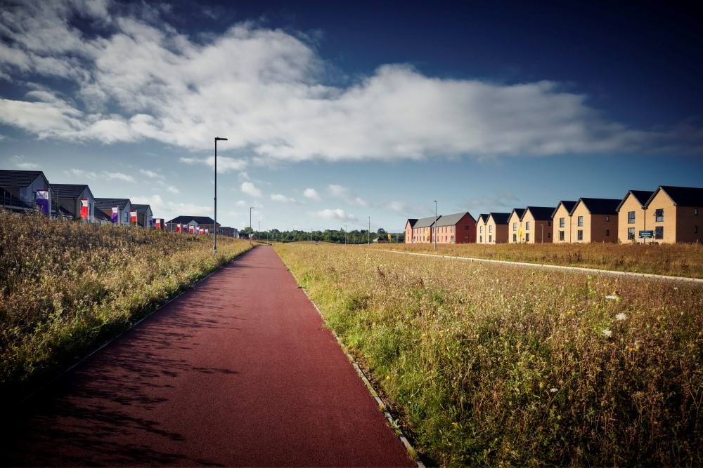 This image: a photo of a redway in Milton Keynes, running
					 through a greenspace between houses on a sunny day. The map: the map
					 shows the proposed redways and existing footpaths and bridleways to
					 be retained in the site, in addition to the wider existing public
					 rights of way outside the site. There are also map markers which show
					 information about the proposed active travel enhancements, when
					 clicked on.